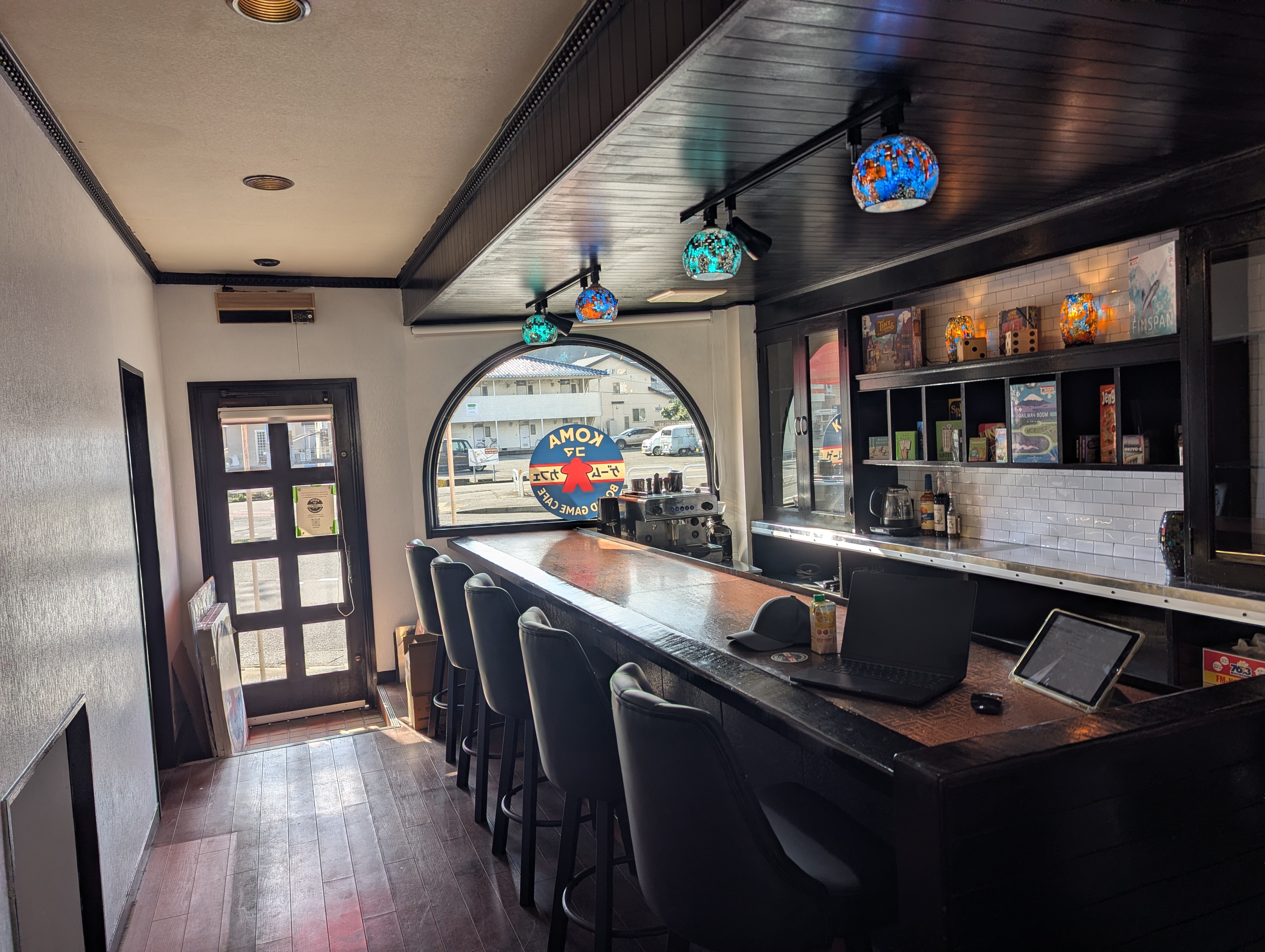 Inside Koma Board Game Café — a long counter, stools, and shelves of board games